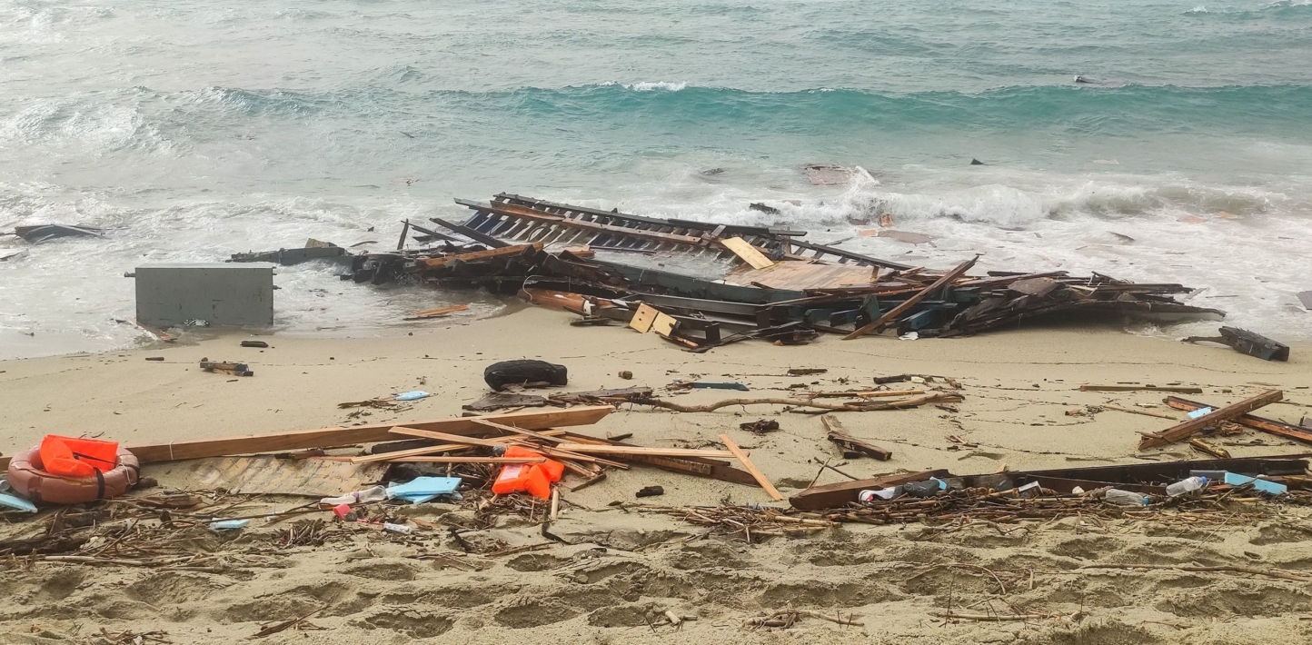 Debris of a shipwreck washed ashore in Steccato di Cutro, south of Crotone, Italy. Wooden slats lie on the shore with a few orange life vests.