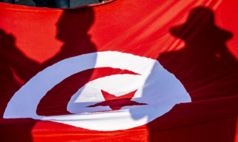 Shadows of Tunisians reflect on a Tunisian flag.