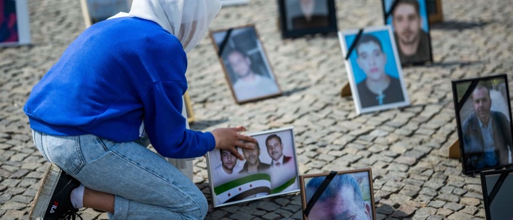 A protester places portraits of Syrians suspected of being detained or disappeared by the Syrian government on the pavement during a demonstration in front of Berlin's Brandenburg gate on May 7, 2022.