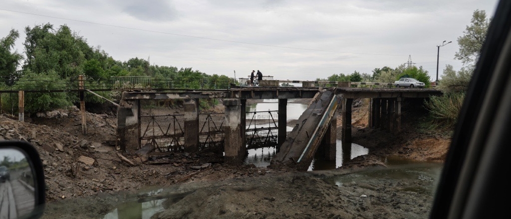A bridge destroyed during a flood following the destruction of the Kahkhovka dam with two men standing on its remnants