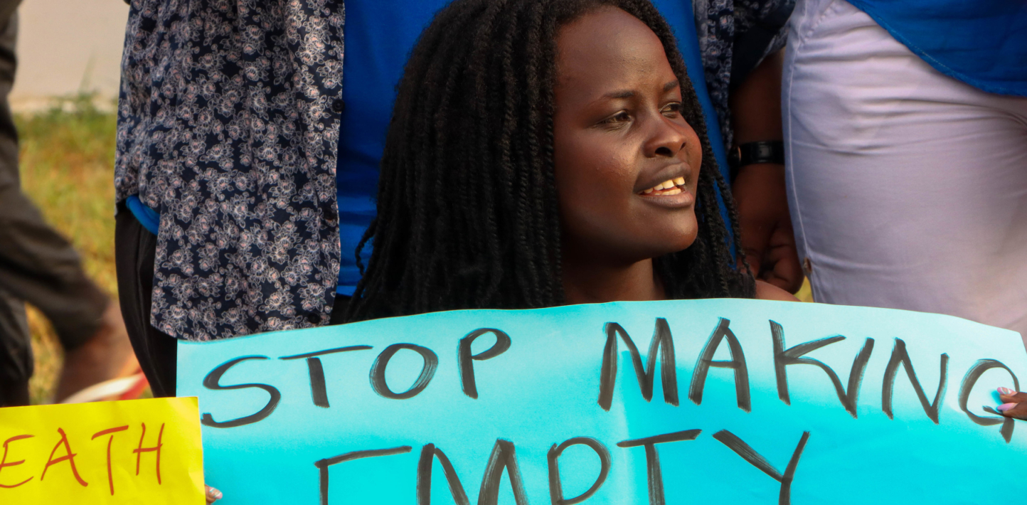 A young Black protester holds up a sign saying "Stop making empty promises"