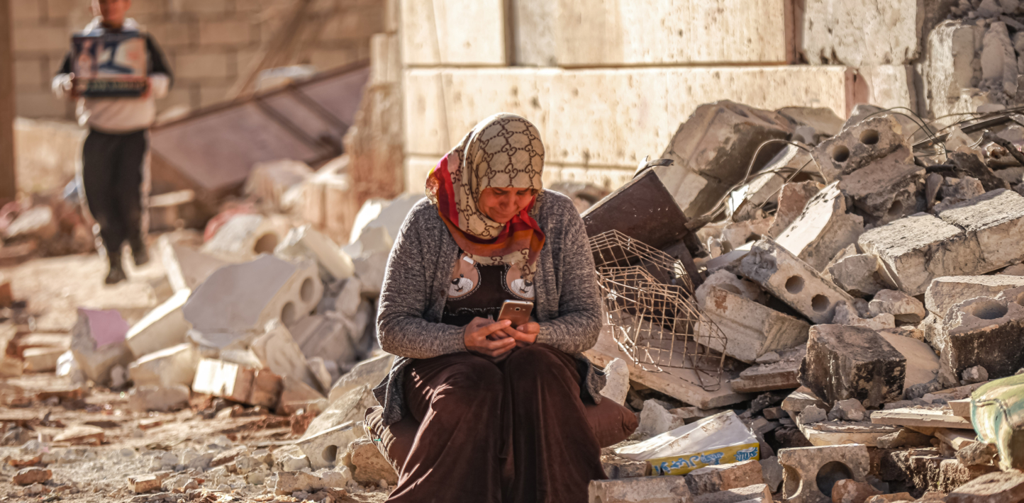 A Syrian woman sits on a debris of a house