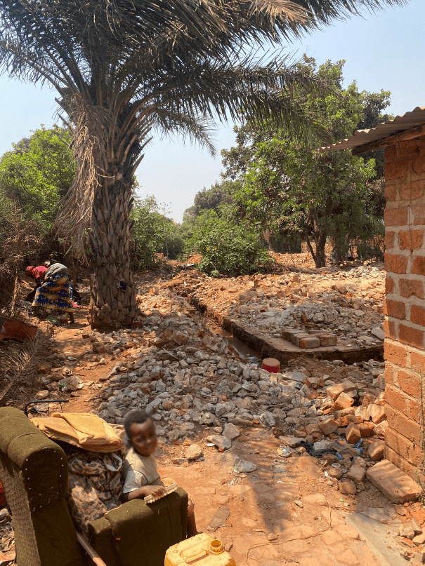 A child sits in the ruins of a house.