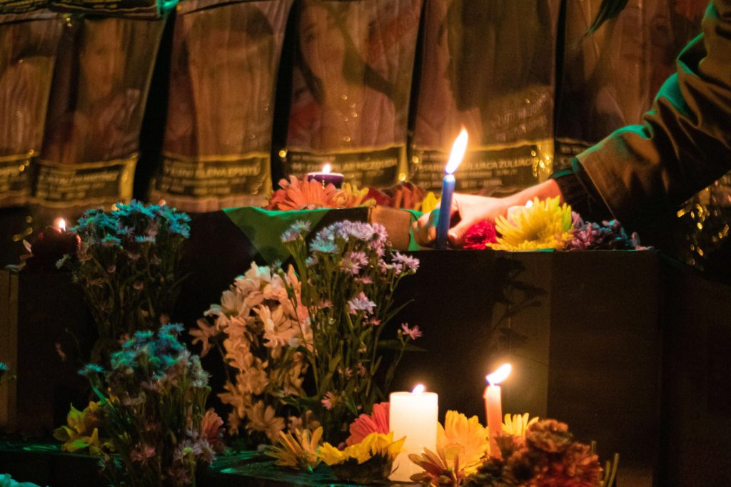 candles and flowers are placed in front of photographs of women who have either disappeared or were killed. 