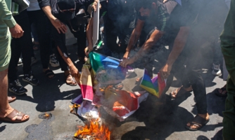 Supporters of Iraq's Sadrist movement burn posters depicting the LGBTQ+ flag during a protest in Basra on June 30, 2023, denouncing the burning of Islam's holy book in Sweden. The protest came a day after an Iraqi citizen living in Sweden, Salwan Momika, 37, stomped on the Islamic holy book and set several pages alight in front of the capital's largest mosque. Swedish police had granted him a permit in line with free-speech protections, but authorities later said they had opened an investigation over "agitation". (Photo by Hussein FALEH / AFP) (Photo by HUSSEIN FALEH/AFP via Getty Images)
