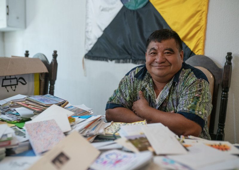 Man sits at a table with a pile of letters.