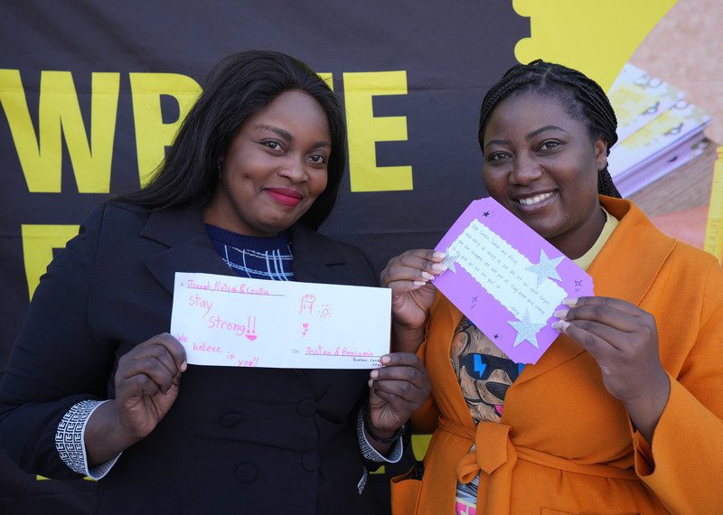 Two women holding letters.