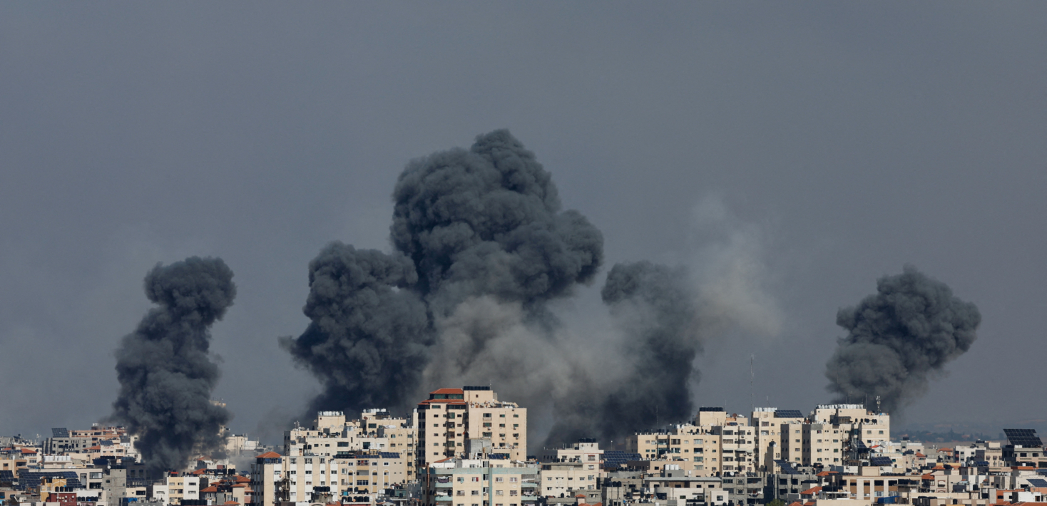 The image shows smoke rising from residential buildings following Israeli strikes in Gaza.