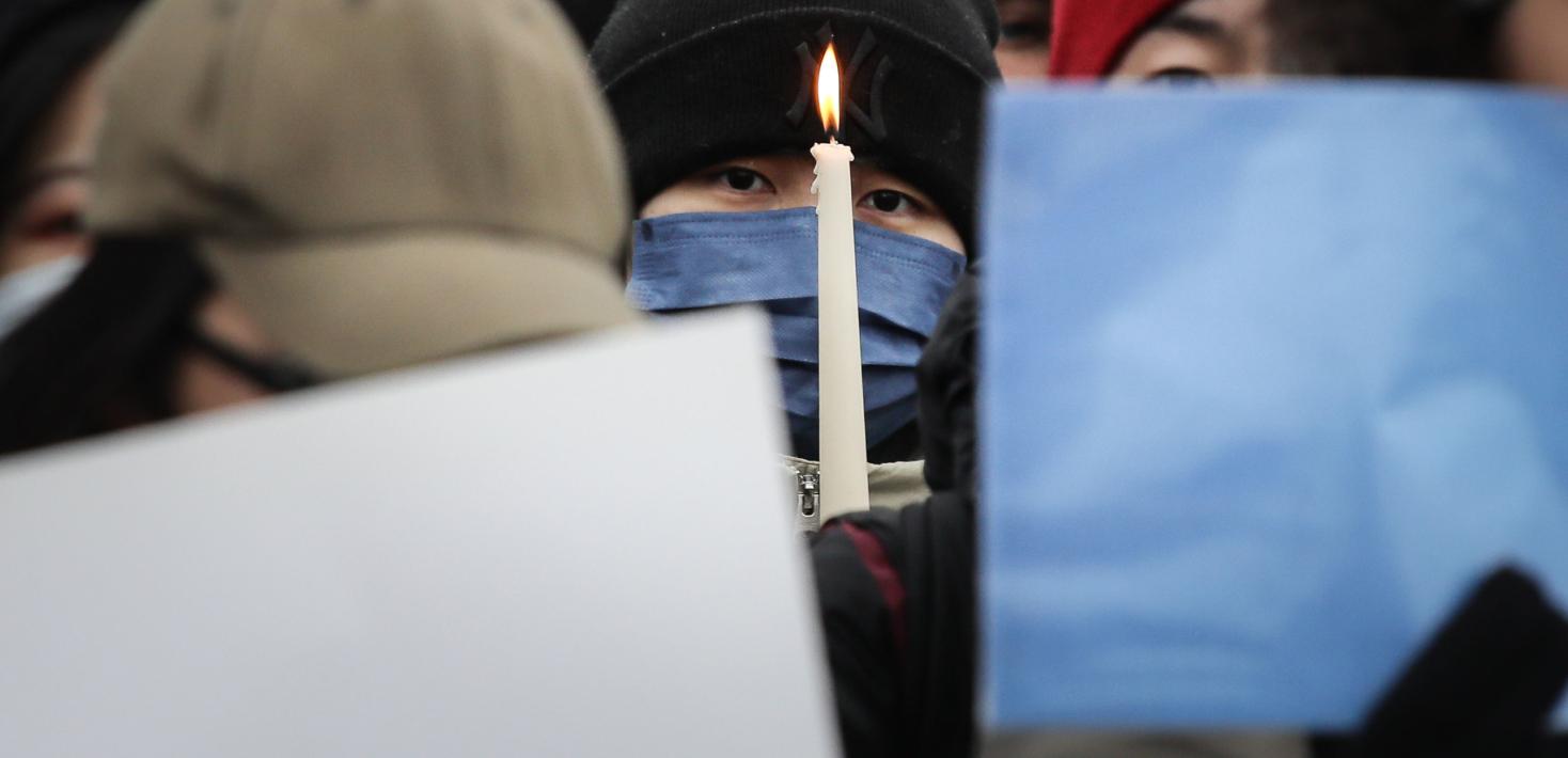 A participant holds a candle as demonstrators protest in front of the Chinese Embassy in solidarity with protesters in China.