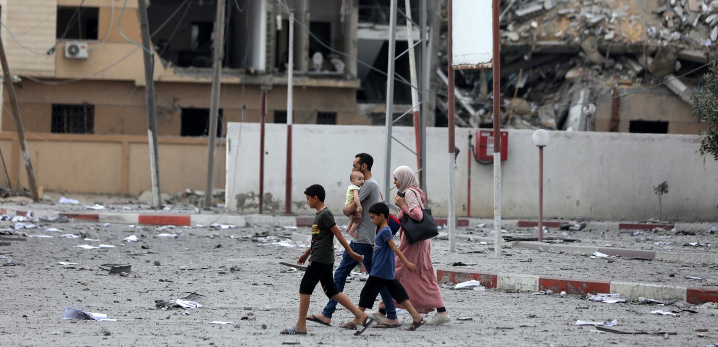 A family walks amongst the rubble, caused by an Israeli airstrike in Gaza