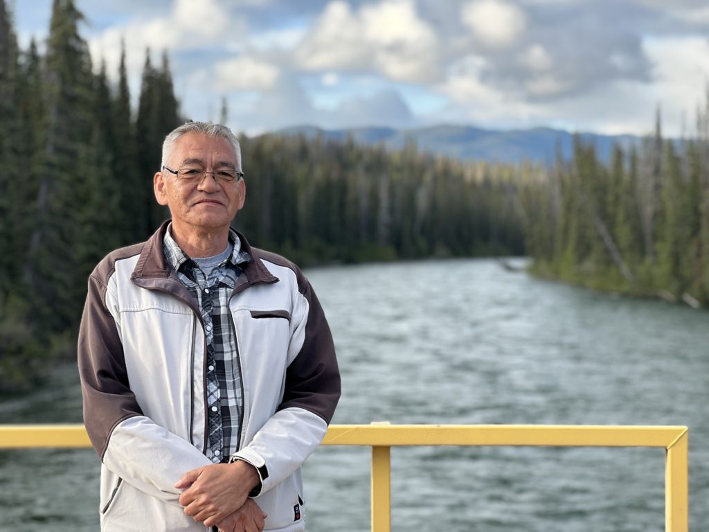 Chief Na’Moks, one of the Hereditary Chiefs of the Wet’suwet’en Nation, stands in front of a river in the woods