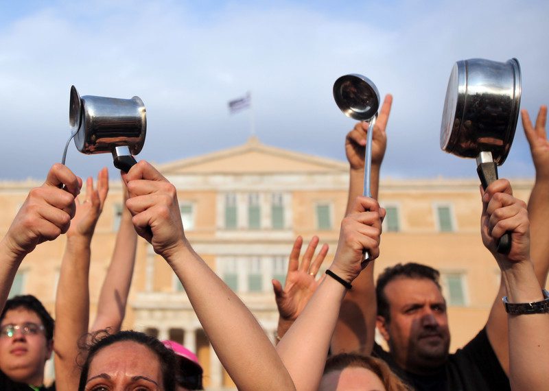 A crowd of hands in the air holding pots and pans.