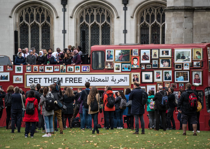 Fotografías de personas sirias desaparecidas adheridas a un autobús en el que hay subidas varias personas, entre ellas un grupo de mujeres sirias, durante una manifestación de “Familias por la Libertad” en la plaza del Parlamento de Londres, Inglaterra.