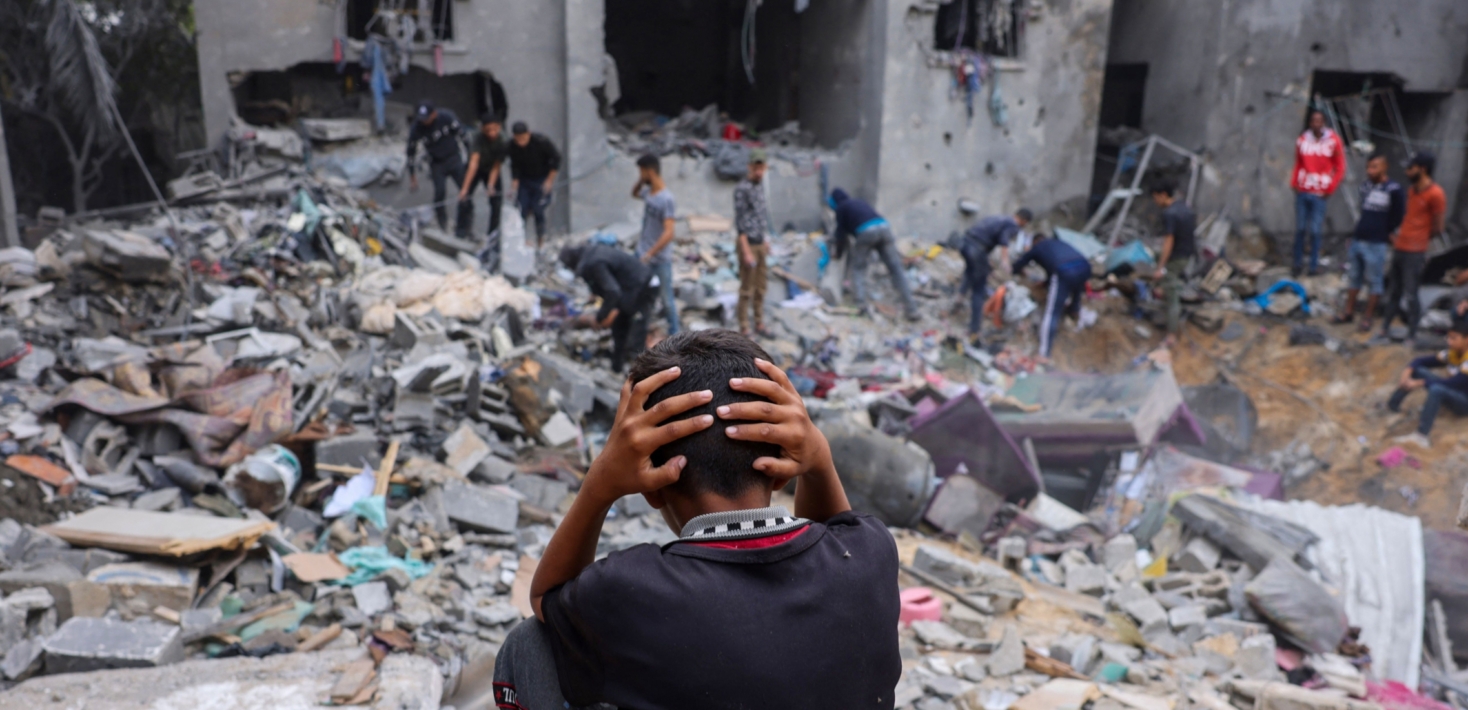 A child holds their head in their hands as people try to salvage belongings from properties wrecked by strikes in Rafah in the southern Gaza Strip