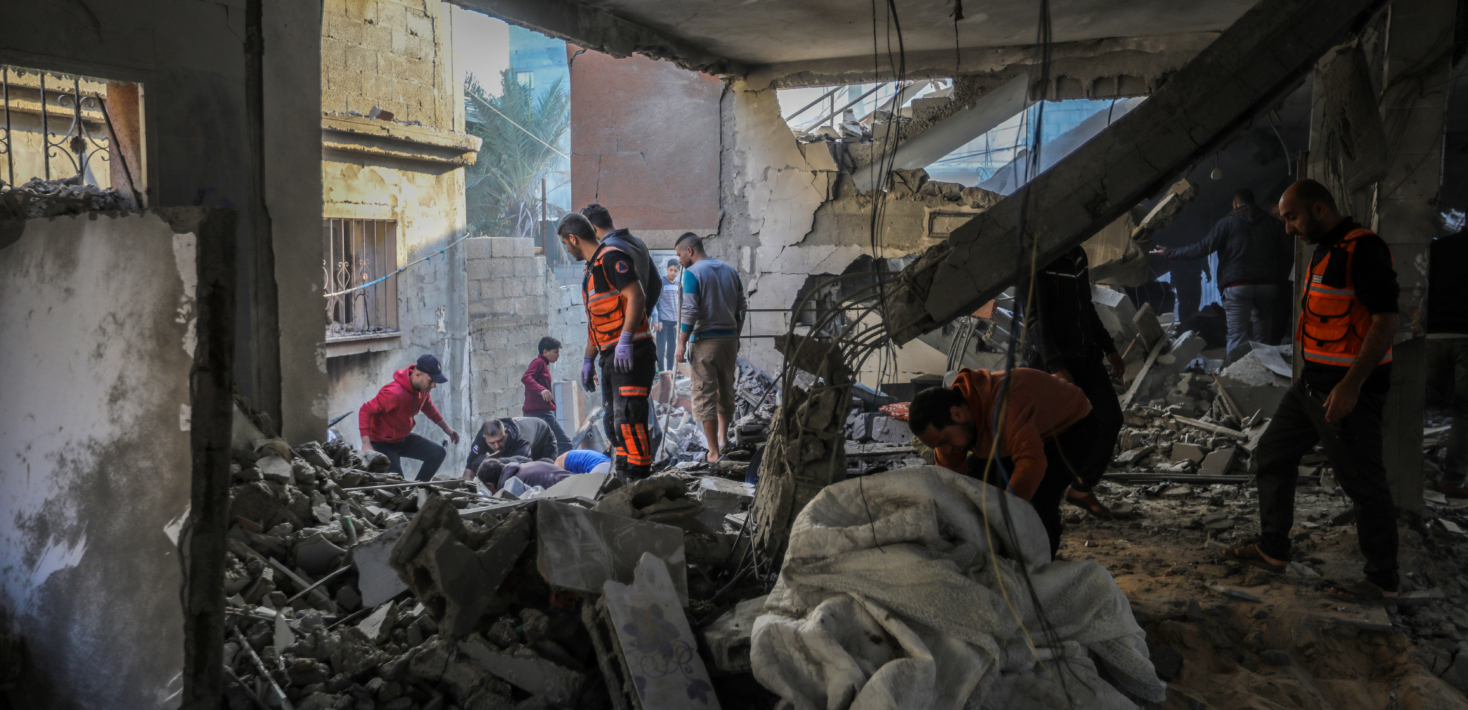 Palestinian residents in Gaza inspect the destruction caused by air strikes on their homes on December 01, 2023 in Khan Yunis, Gaza. In the image, rescue workers wearing red uniform as well as people in civilian clothing are seen standing amonst the rubble inside a destroyed building. Photo credit: Ahmad Hasaballah/Getty Images) on 1 December, 2023.