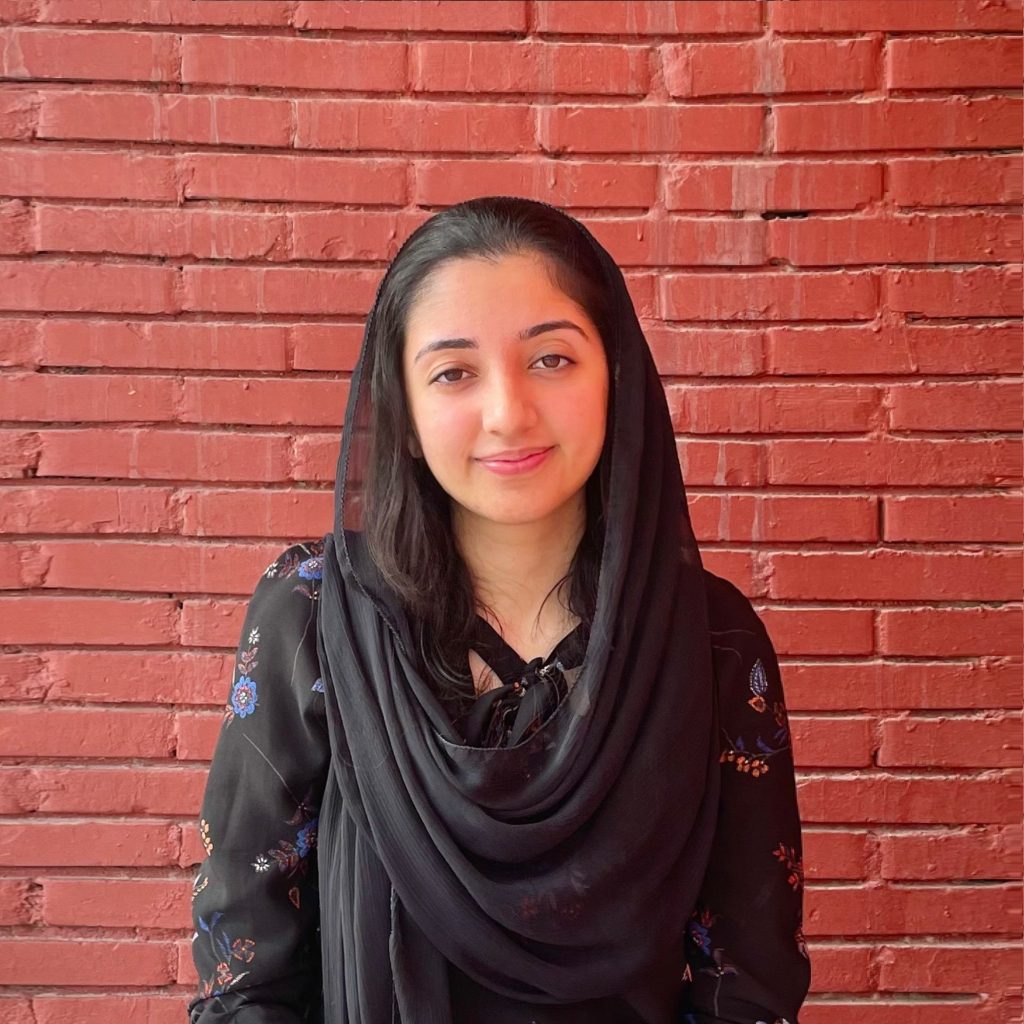 Duaa Shah standing in front of a red brick wall.