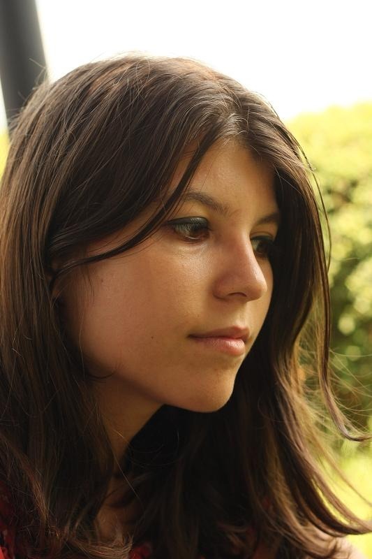 Portrait of a young woman with dark hair looking downwards in a thoughtful manner