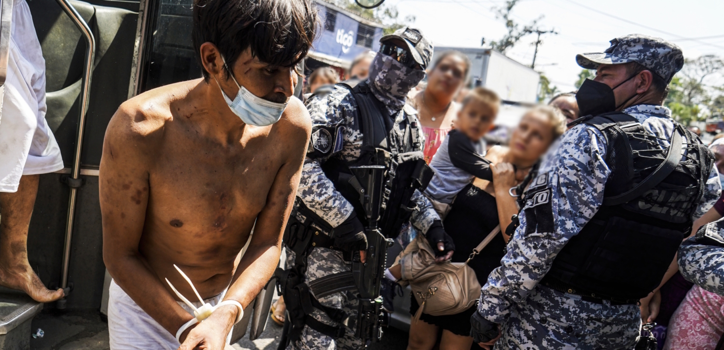 Police officers in El Salvador escort an alleged gang member into a detention center.