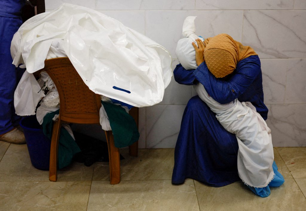 Palestinian woman Inas Abu Maamar embraces the body of her 5-year-old niece Saly, who was killed in an Israeli strike, at Nasser hospital in Khan Younis in the southern Gaza Strip