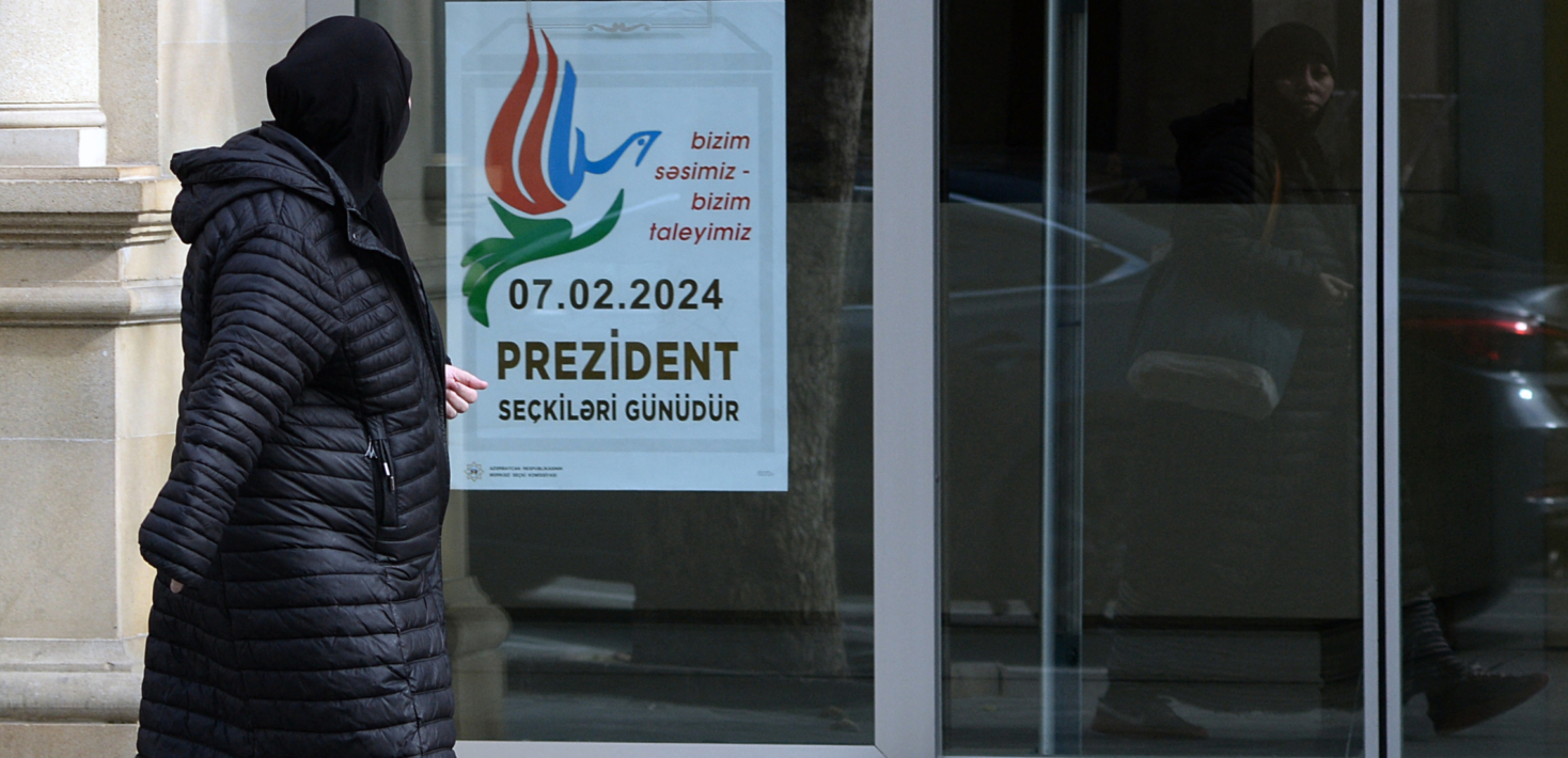 A woman walks past a poster informing on the upcoming snap presidential election in Baku