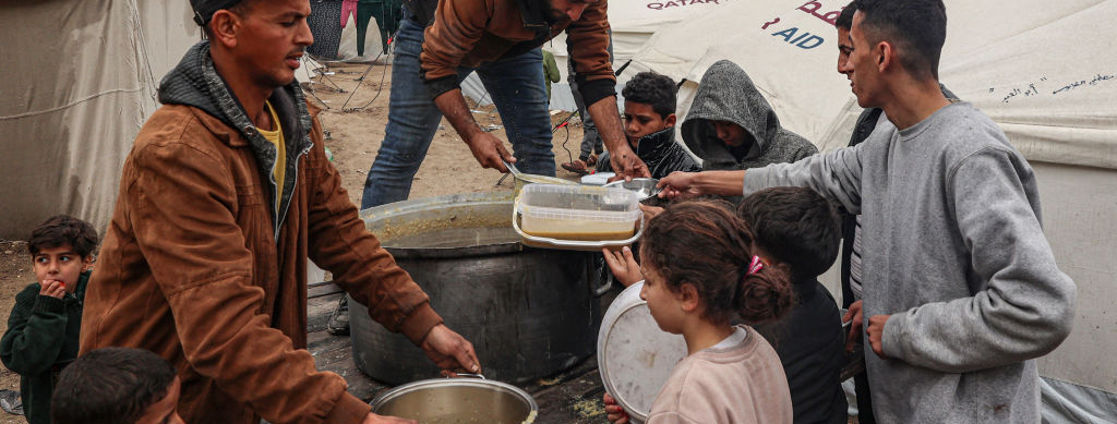 Volunteers distribute rations of red lentil soup to displaced Palestinians in Rafah in the southern Gaza Strip on February 18, 2024, amid the ongoing war on Gaza.