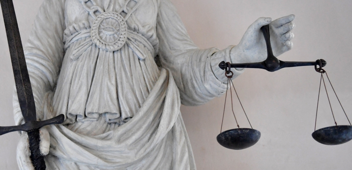 statue of justice in white holding scales and a sword