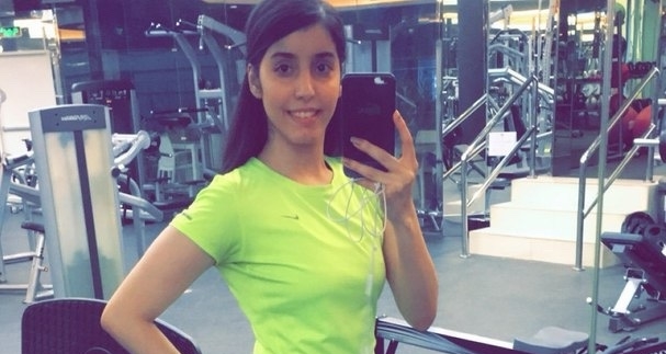 Photo of Manahel el Otaibi, detained by Saudi authorities for speaking out for women's rights, posing for a photo at the gym wearing a lime yellow tshirt and sports leggings without the traditional headress or hijab.