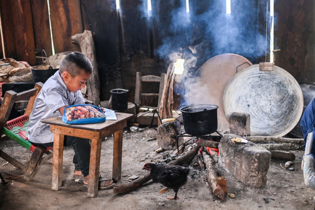un jeune enfant autochtone fait ses devoirs sur une petite table