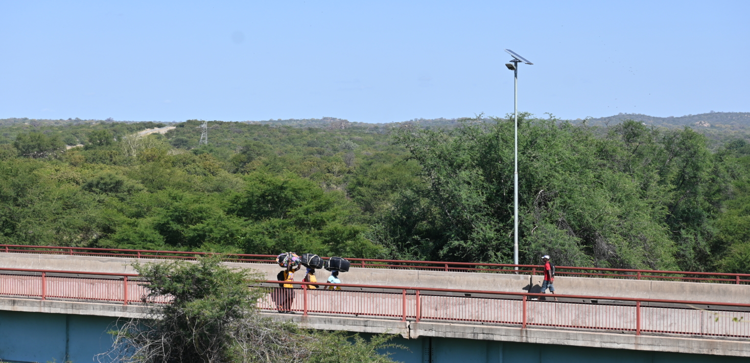 Women Cross border traders carry their wares across a bridge.
