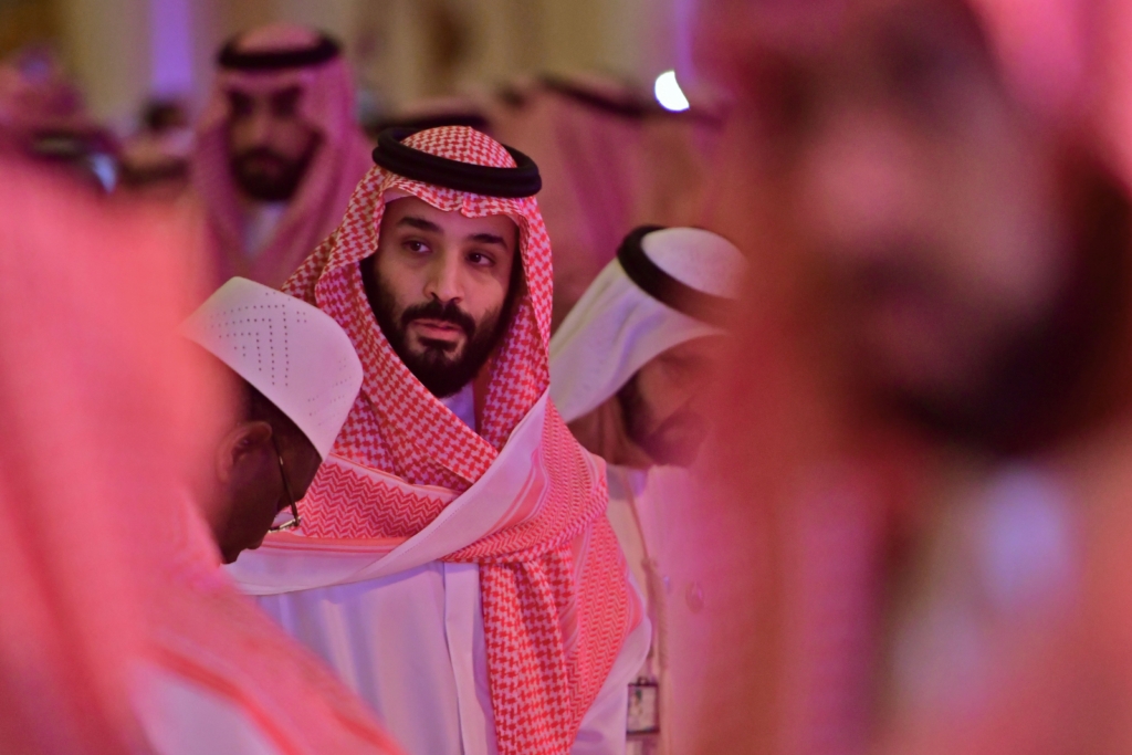 Saudi Crown Prince at a conference in Riyadh, surrounded by other attendees. 