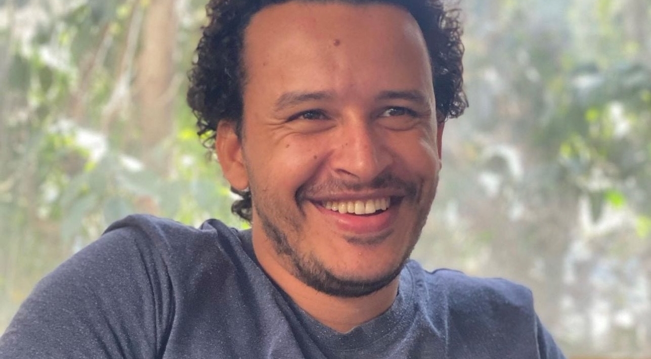 Portrait photo of anti-torture protester Mahmoud Hussein wearing a grey T-Shirt and smiling.