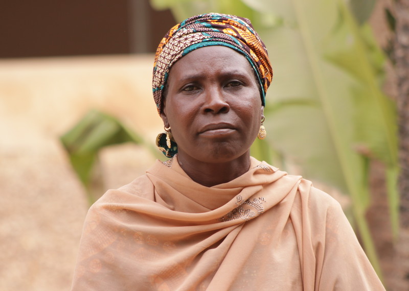 A mother, with a peach scarf and colourful headscarf gazes into the camera.