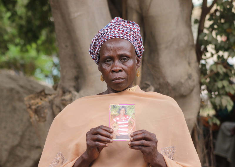 A lady draped in a cream wrap, holds up a picture of her missing daughter.