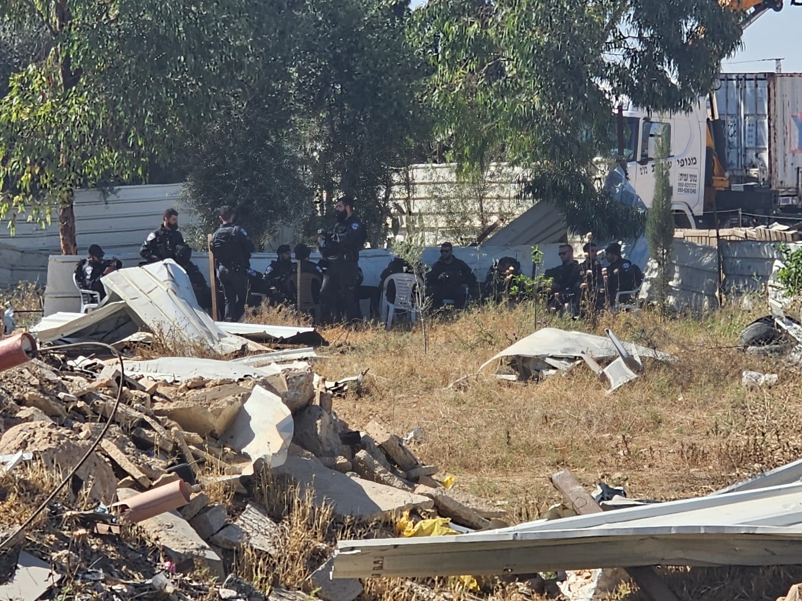 Israeli police sit beside a destroyed home in Wadi Al-Khalil