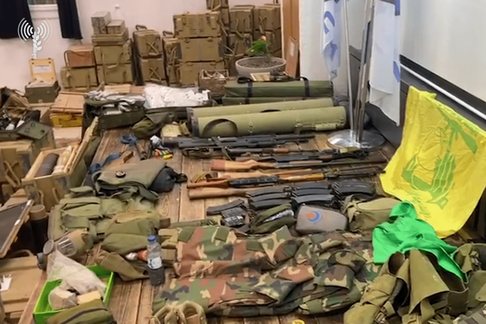 Weapons, military equipment and a Hezbollah flag are displayed in a room