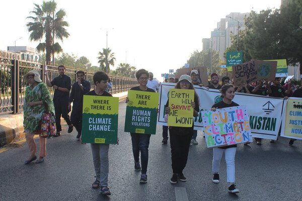 People protesting on the streets of Islamabad holding placards with Amnesty International logos. The placards say "Where there is climate change..."; "There are human rights violations" and "Youth Climate Action"