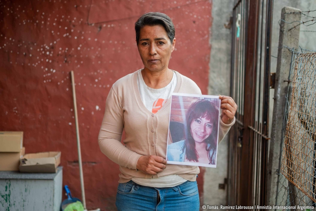A woman with short salt and pepper hair, holds up a picture of Sofia Fernandez.