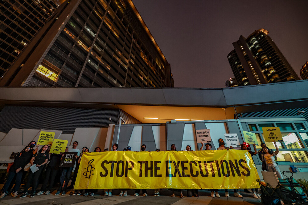 a group of people holding a large yellow banner that says stop the executions