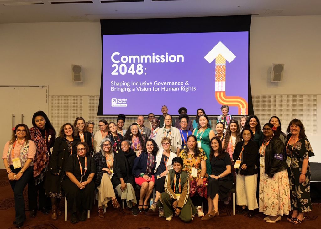 Members of the 2048 Commission pose in front of a screen at the Women Deliver conference