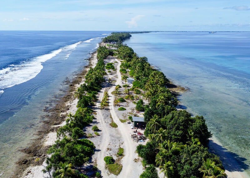 An overhead shot shows a thin strip of land in a coastal tropical landscape