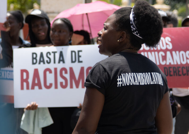 A woman stands in front of anti-racism protestors