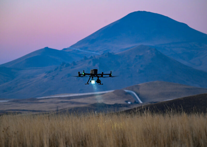A drone flies over a mountainous landscape at sunset