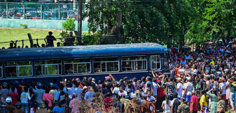 A bus surrounded by a large crowd