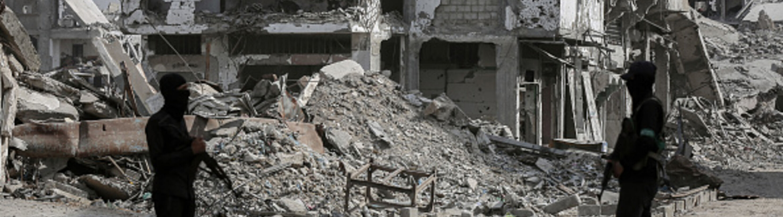 Hamas fighters stand before a destroyed building in Gaza