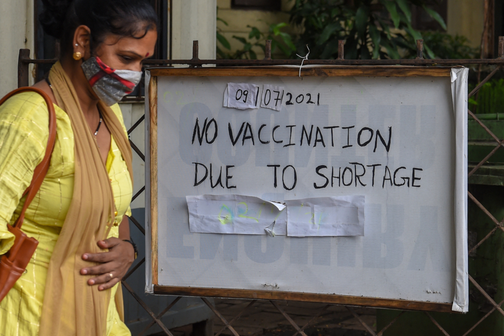 Una mujer pasa por delante de un cartel donde se lee: “No hay vacunación por desabastecimiento”.