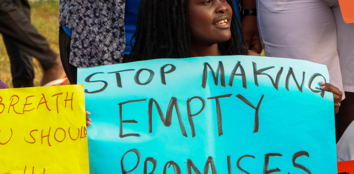 Una mujer sostiene un cartel en el que se lee: "No más promesas vacías".