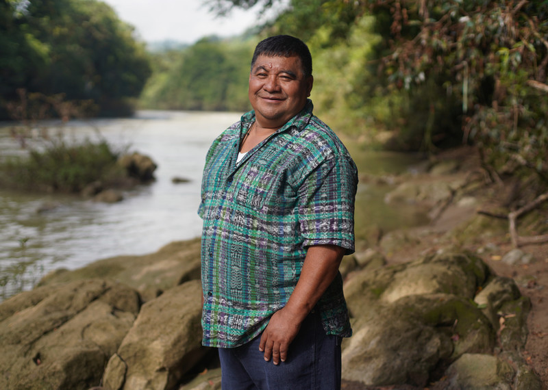 Bernardo Caal Xol posa sonriente junto a un río.