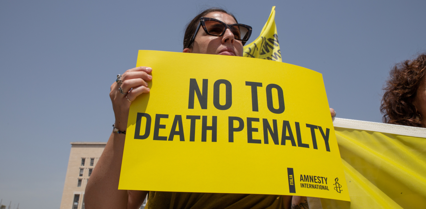 Una activista sostiene una pancarta amarilla con el logotipo de Amnistía Internacional: “No a la pena de muerte”.