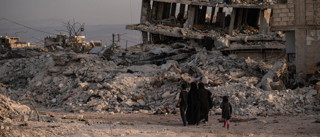 Una familia camina a través de edificios destruidos en la ciudad de Jindires el 28 de febrero de 2023 cerca de Alepo, Siria. En la madrugada del 6 de febrero se produjo cerca de Gaziantep, Turquía, un terremoto de magnitud 7,8, seguido de otro de magnitud 7,5 justo después de mediodía. Según la población local, casi 1.400 personas murieron, y la ciudad sufrió graves daños. Los terremotos causaron una destrucción generalizada en el sur de Turquía y el norte de Siria y mató a más de 40.000 personas.
