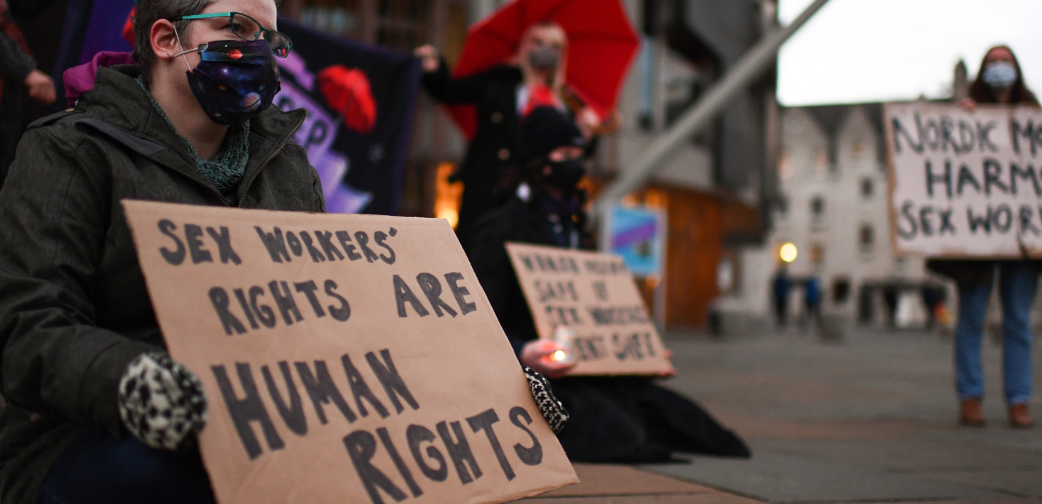 manifestante sostiene un cartel que dice que los derechos de las personas que ejercen el trabajo sexual son derechos humanos